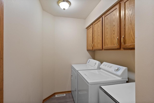 laundry room with cabinets, dark hardwood / wood-style floors, and washer and clothes dryer