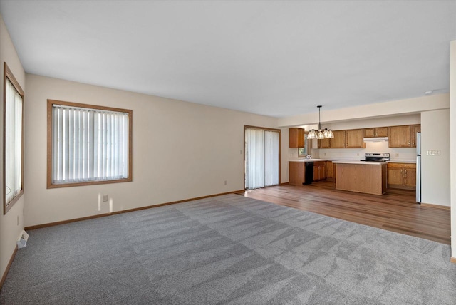 unfurnished living room with light carpet and a chandelier