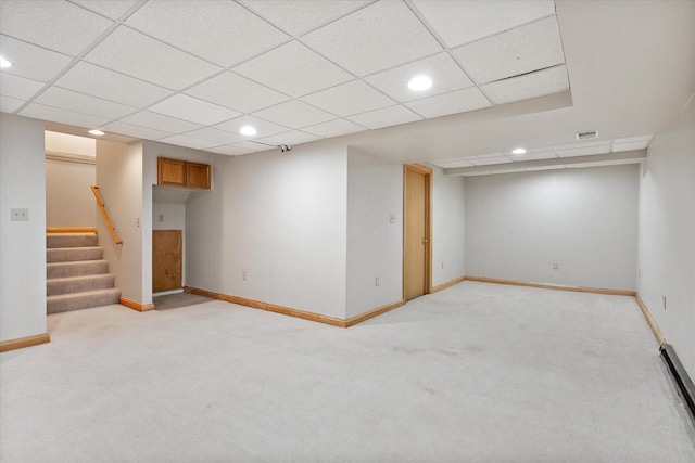 basement with light carpet and a paneled ceiling