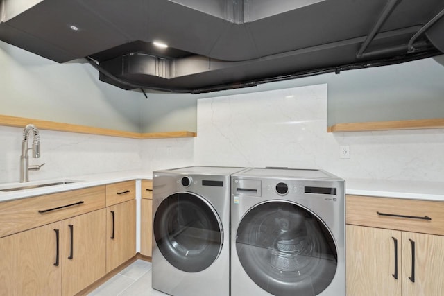 laundry area featuring sink, light tile patterned floors, cabinets, and independent washer and dryer