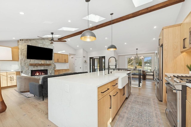 kitchen with appliances with stainless steel finishes, pendant lighting, light wood-type flooring, and a spacious island