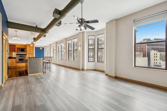 unfurnished living room with ceiling fan and light hardwood / wood-style flooring