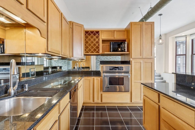 kitchen featuring pendant lighting, sink, dark stone countertops, oven, and backsplash