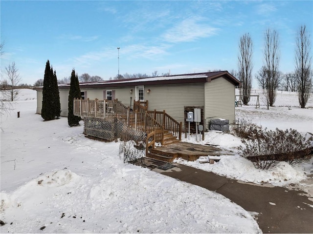 snow covered back of property with a deck