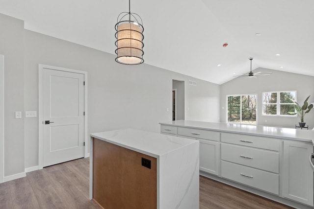 kitchen featuring white cabinetry, decorative light fixtures, vaulted ceiling, and a kitchen island