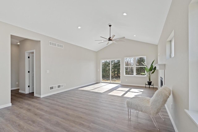 living room with light hardwood / wood-style flooring, high vaulted ceiling, and ceiling fan