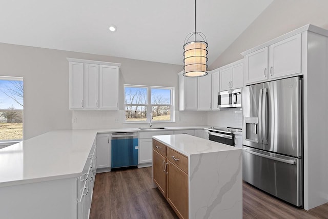 kitchen featuring stainless steel appliances, a kitchen island, hanging light fixtures, and white cabinets