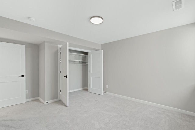 unfurnished bedroom with light colored carpet and a closet