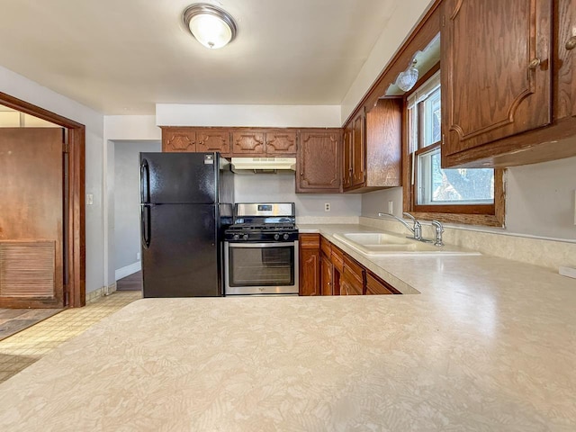 kitchen with black refrigerator, sink, and stainless steel gas stove