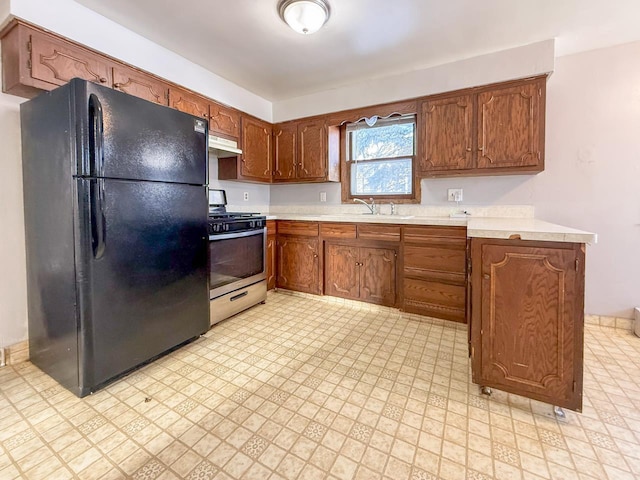 kitchen featuring sink, gas range, and black fridge