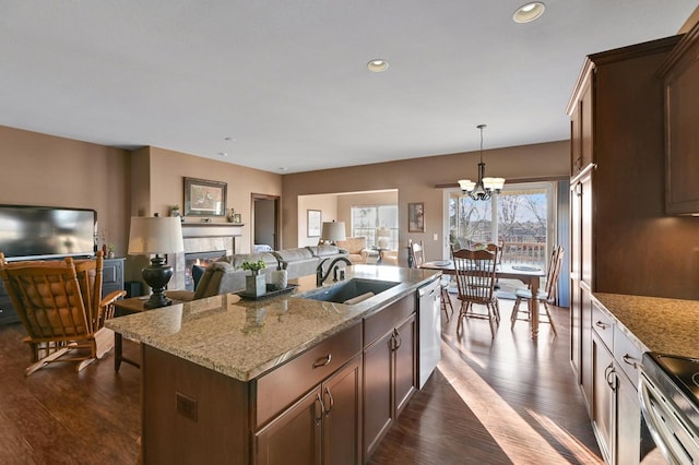 kitchen with sink, appliances with stainless steel finishes, an island with sink, pendant lighting, and a fireplace