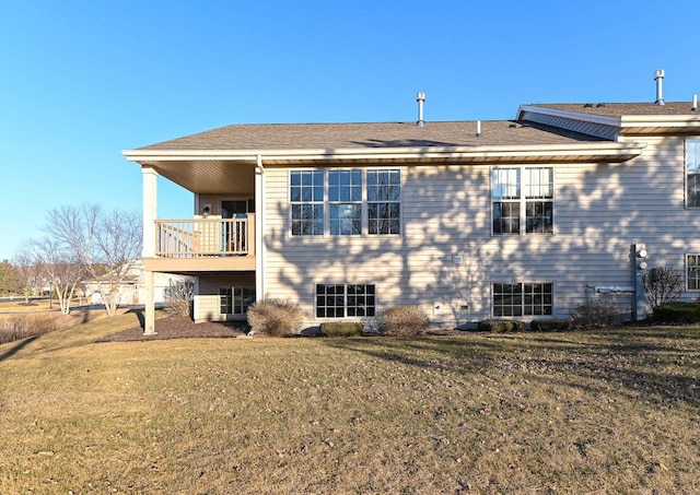 rear view of property featuring a balcony and a yard