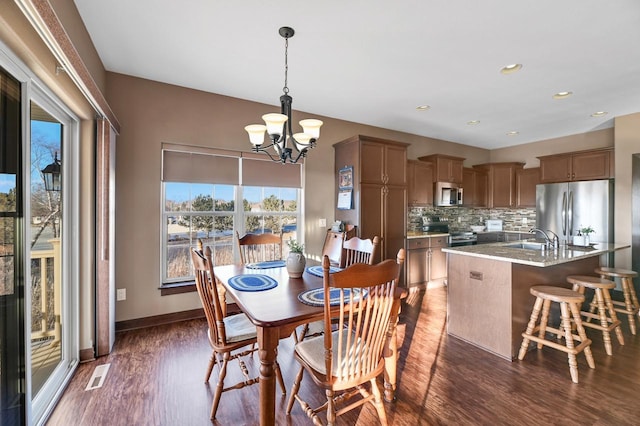 dining room with sink, a notable chandelier, and dark hardwood / wood-style flooring