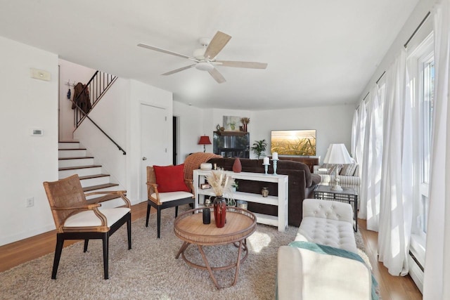 sitting room with baseboard heating, ceiling fan, and light wood-type flooring