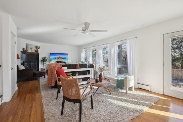 living room with baseboard heating, a healthy amount of sunlight, and hardwood / wood-style floors