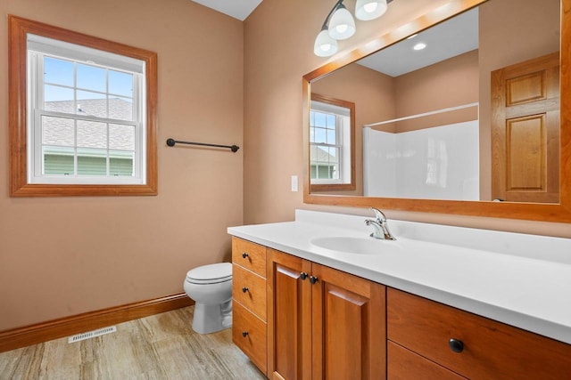 bathroom featuring walk in shower, vanity, toilet, and hardwood / wood-style floors