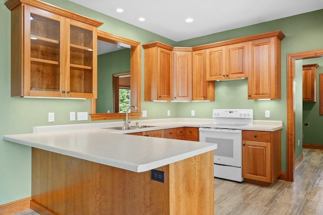 kitchen with white electric range, kitchen peninsula, sink, and light hardwood / wood-style flooring