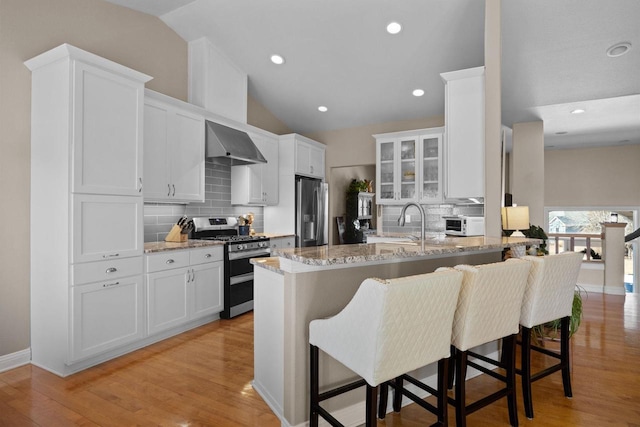 kitchen featuring stainless steel appliances, white cabinetry, light stone countertops, and a kitchen breakfast bar