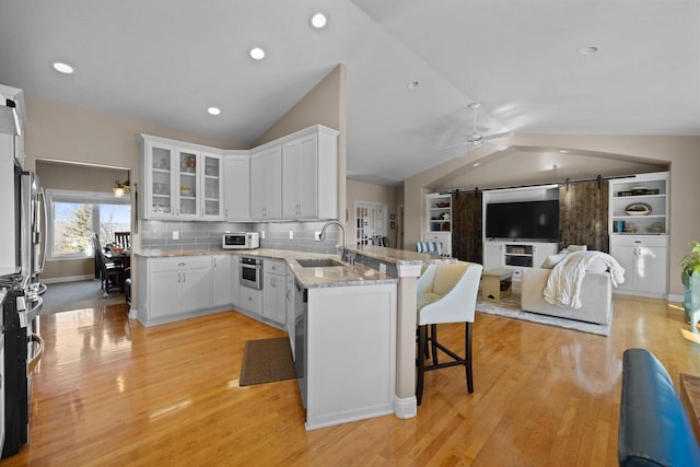 kitchen with white cabinetry, sink, a breakfast bar area, kitchen peninsula, and a barn door