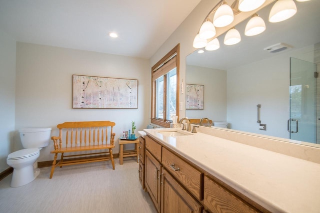 bathroom featuring vanity, a shower with shower door, and toilet