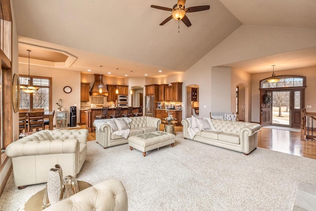 living room with high vaulted ceiling and ceiling fan with notable chandelier