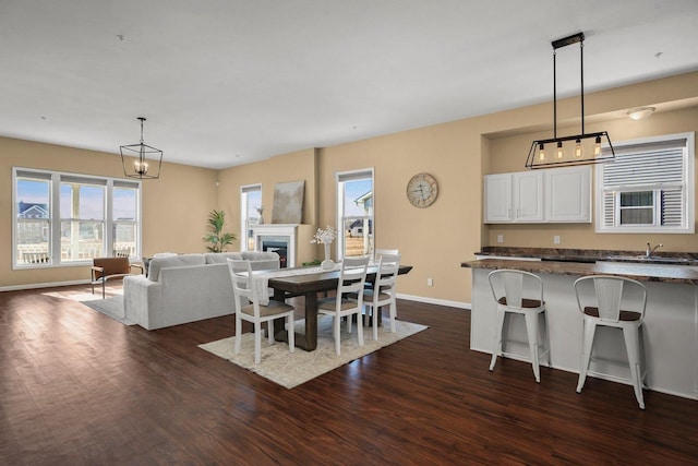 dining space with dark hardwood / wood-style flooring, sink, a healthy amount of sunlight, and an inviting chandelier