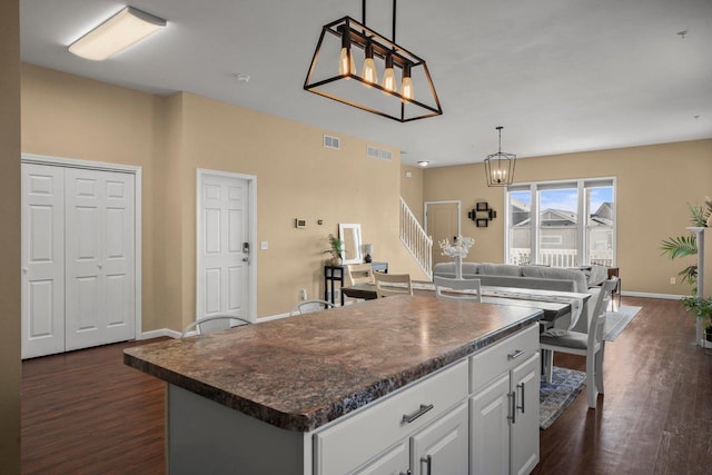 kitchen featuring decorative light fixtures, a center island, dark hardwood / wood-style floors, a notable chandelier, and white cabinets