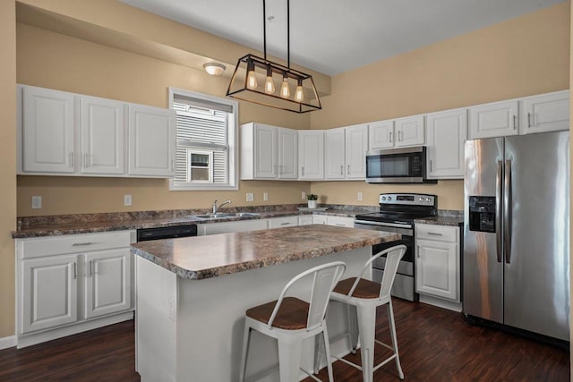 kitchen featuring a kitchen island, pendant lighting, sink, white cabinets, and stainless steel appliances