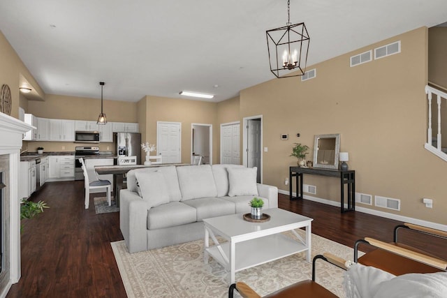 living room with sink, a notable chandelier, and dark wood-type flooring