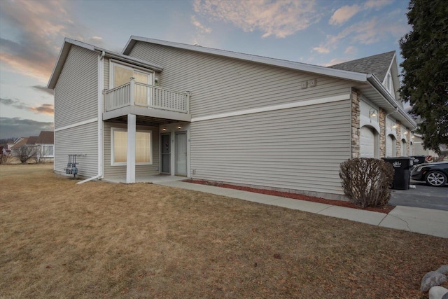 property exterior at dusk with a balcony and a yard