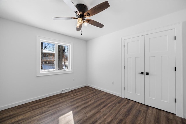 unfurnished bedroom with ceiling fan, dark hardwood / wood-style floors, and a closet