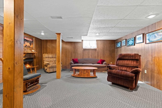 carpeted living room with a drop ceiling and wooden walls