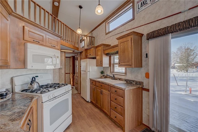 kitchen with a wealth of natural light, white appliances, decorative light fixtures, and a sink