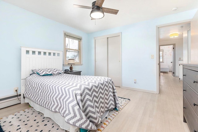 bedroom with a baseboard heating unit, light hardwood / wood-style flooring, a closet, and ceiling fan