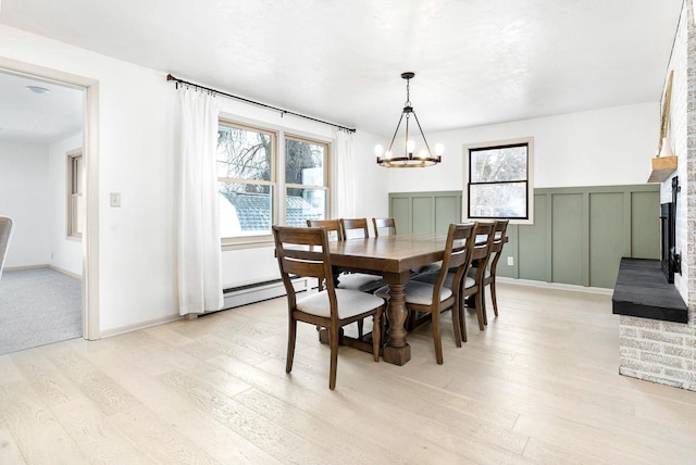 dining space with a brick fireplace, a notable chandelier, and light wood-type flooring