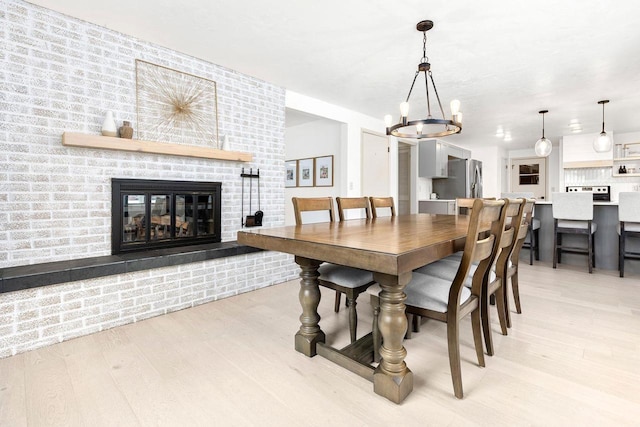 dining room with a notable chandelier, a fireplace, and light wood-type flooring