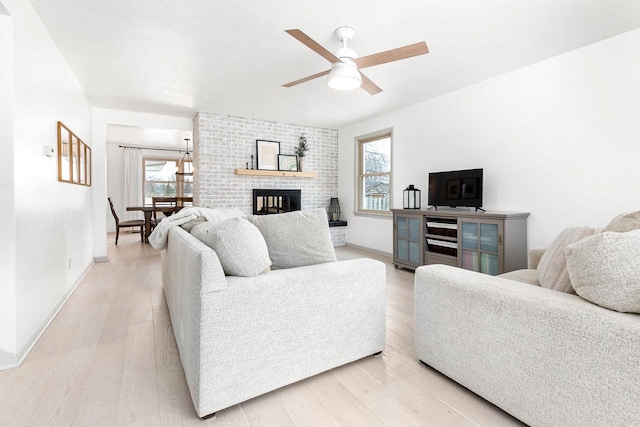 living room featuring hardwood / wood-style flooring, ceiling fan, and a fireplace