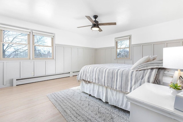 bedroom featuring ceiling fan, baseboard heating, and light hardwood / wood-style floors