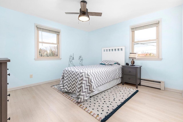 bedroom with ceiling fan, light hardwood / wood-style floors, and a baseboard heating unit