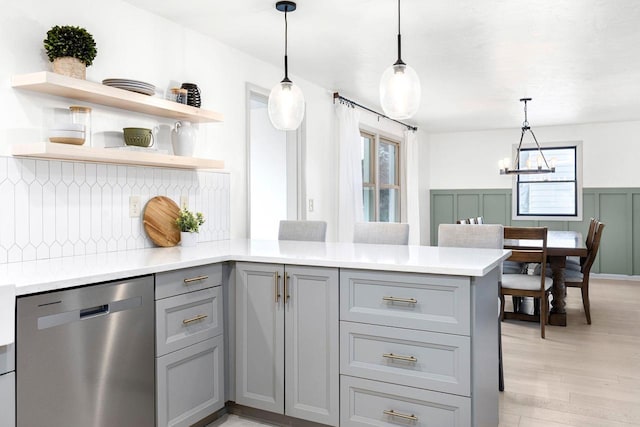 kitchen with pendant lighting, gray cabinetry, stainless steel dishwasher, kitchen peninsula, and light wood-type flooring