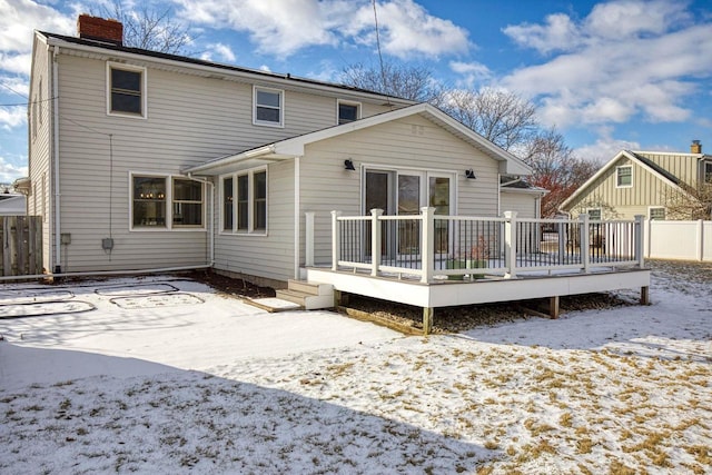 snow covered back of property with a deck