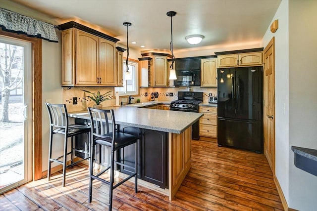 kitchen featuring a breakfast bar, decorative light fixtures, dark hardwood / wood-style floors, decorative backsplash, and black appliances