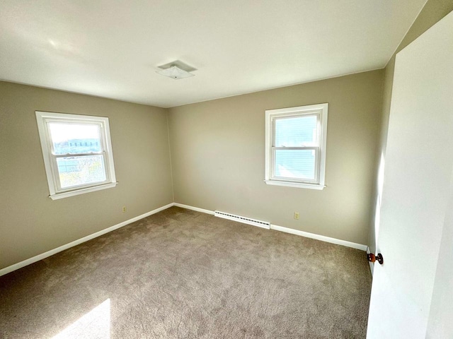 carpeted spare room featuring a baseboard heating unit