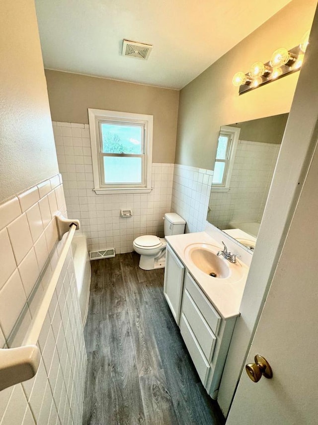 bathroom with tile walls, vanity, wood-type flooring, and toilet