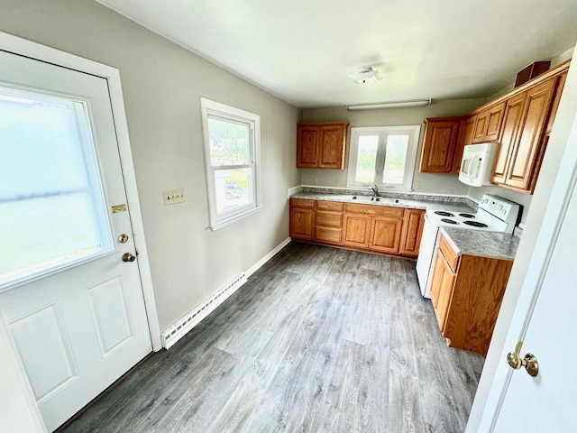 kitchen featuring hardwood / wood-style flooring, white appliances, sink, and a baseboard heating unit