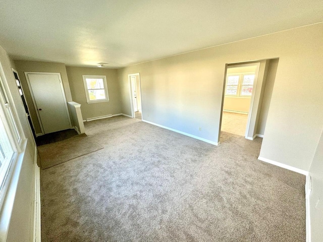 carpeted empty room with a baseboard heating unit