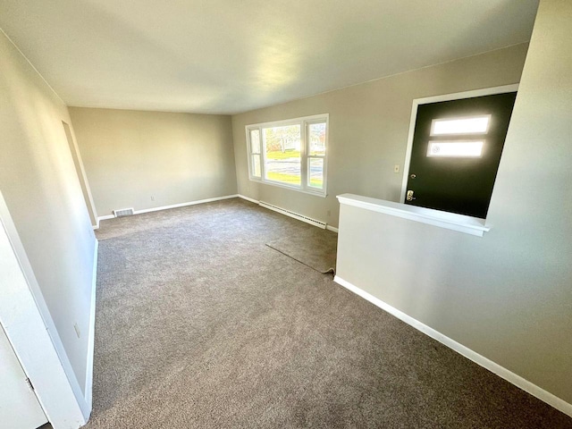 empty room with carpet floors and a baseboard heating unit