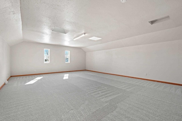 bonus room with lofted ceiling, carpet floors, and a textured ceiling