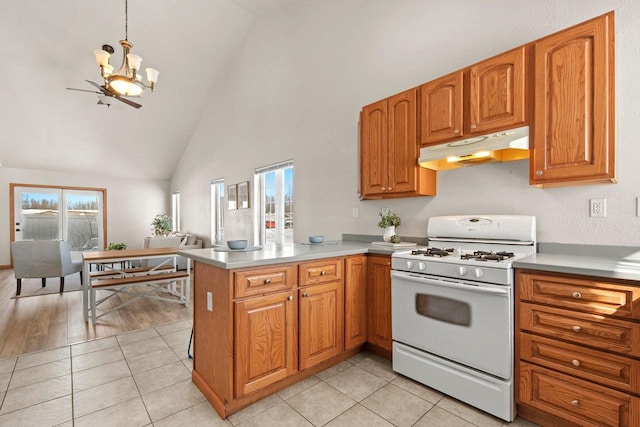 kitchen featuring pendant lighting, gas range gas stove, an inviting chandelier, light tile patterned flooring, and kitchen peninsula