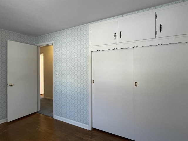 unfurnished bedroom with dark wood-type flooring and a closet